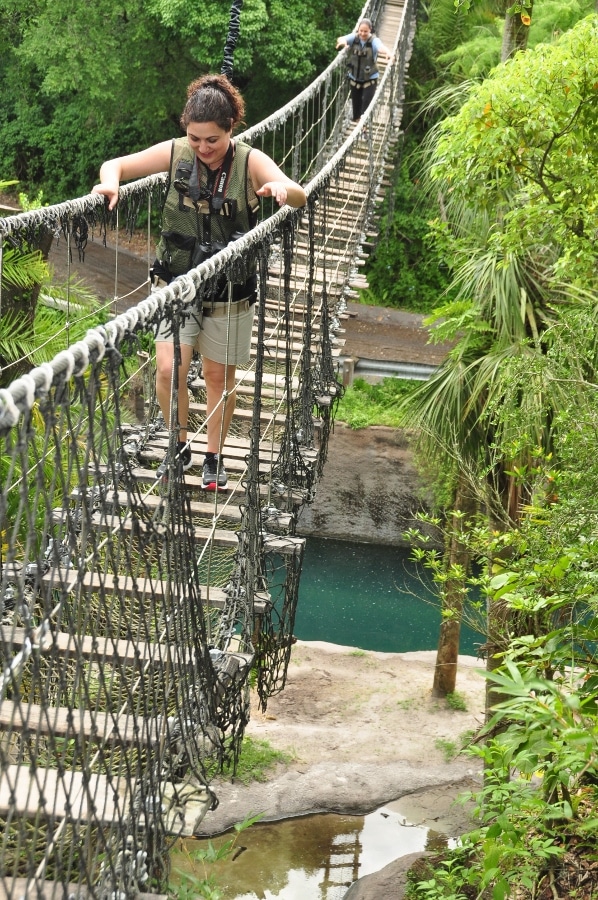 a woman walking across a rope bridge