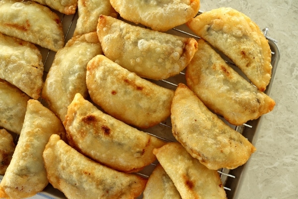 a bunch of fried empanadas on a cooling rack