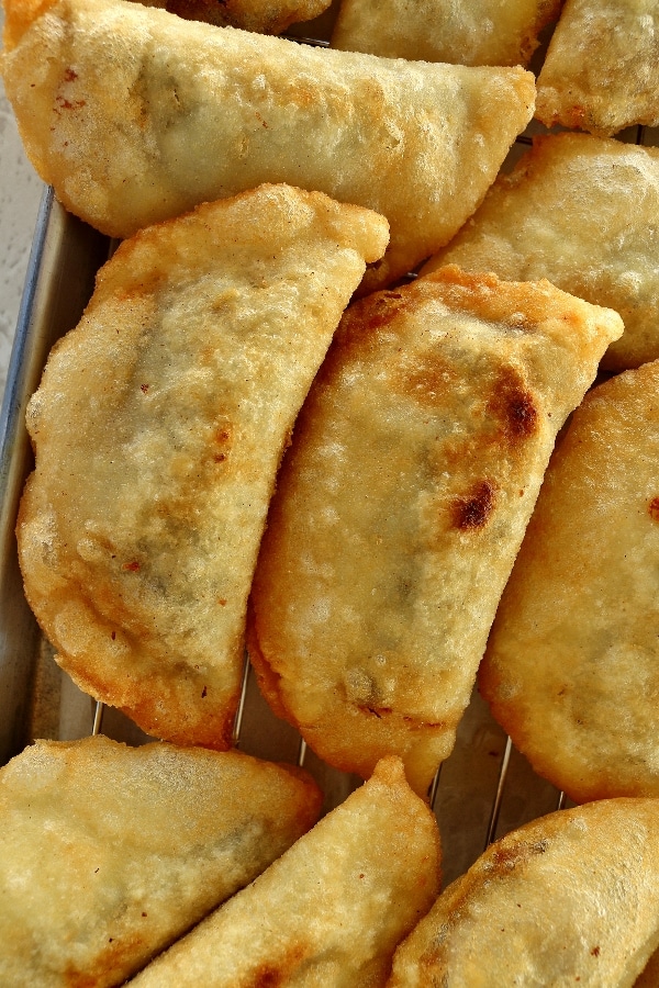 a closeup of fried empanadas on a cooling rack