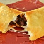 Black bean and cheese empanada ripped in half to show melted cheese