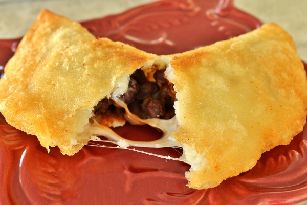 a fried empanada on a red plate, broken in half to show the filling