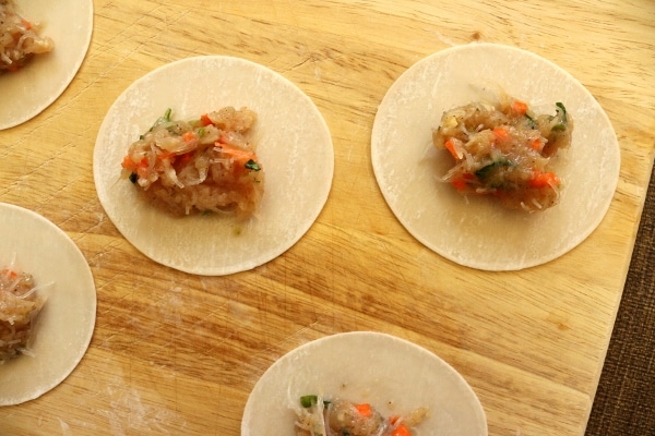 assembling chicken and thai basil dumplings on a wooden board