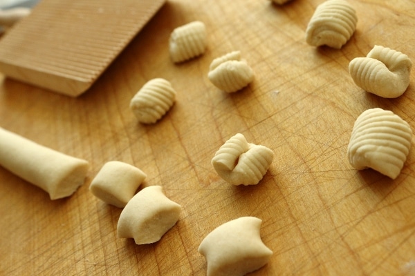 A wooden cutting board with cavatelli with and without ridges on them