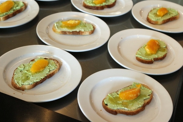 rows of plates topped with toast with green topping and orange segments