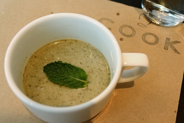 a creamy beverage in a coffee cup topped with mint