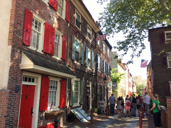 A group of people walking down a street next to a brick building