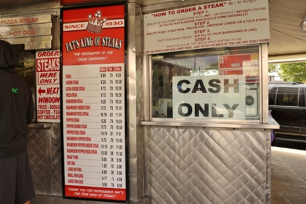 the menu and various signs outside Pat\'s King of Steaks