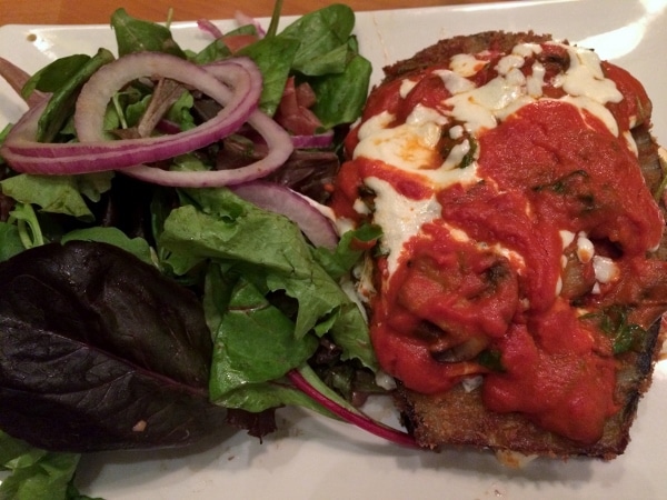 a plate of eggplant parmesan with salad on the side