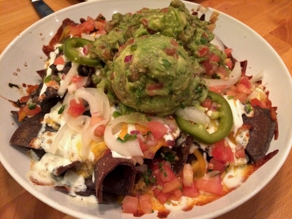 A plate of nachos topped with a large scoop of guacamole