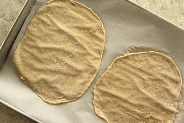 two pieces of thinly rolled out dough on a sheet pan