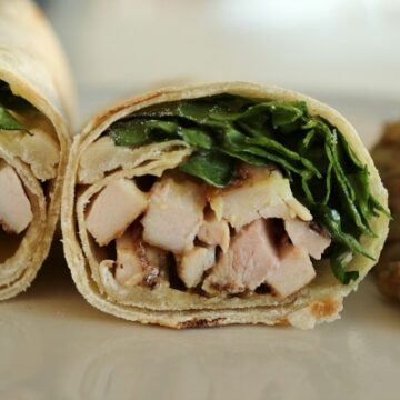 A close up of a cross-section of a wrap with chicken and greens