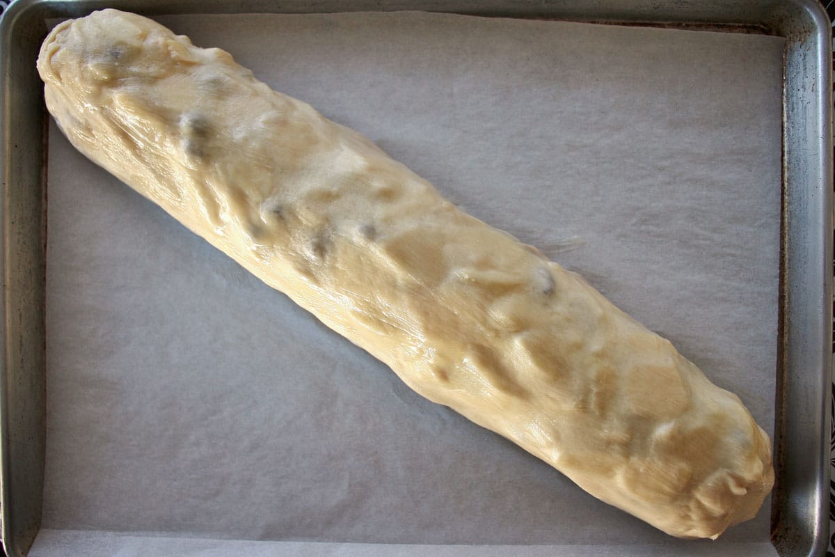 an unbaked strudel roll diagonally placed on a baking sheet.