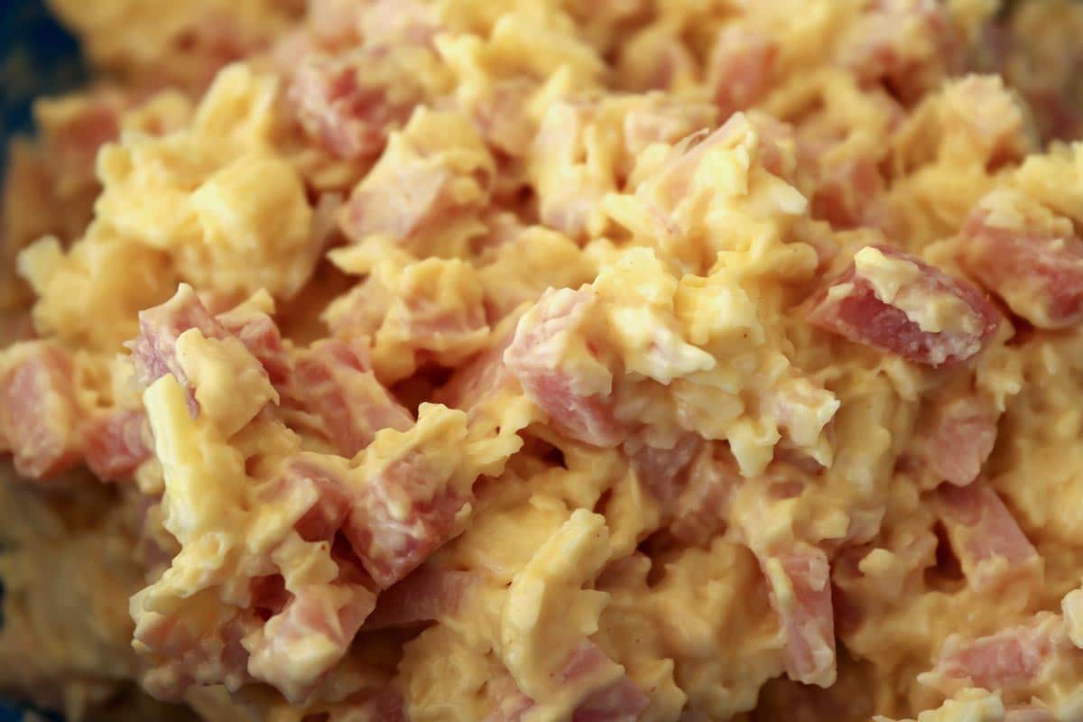 Closeup of chopped ham and shredded cheese combined with mayo and mustard.