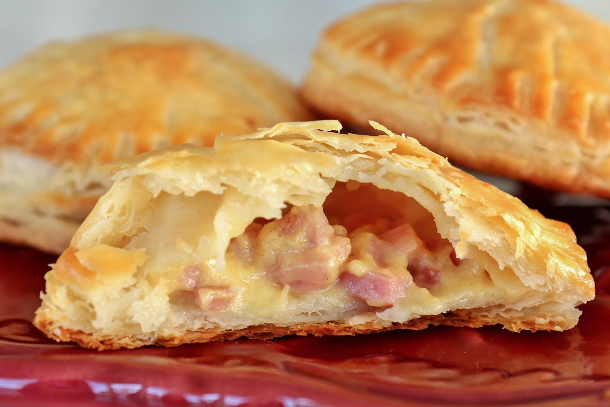 Closeup of a cross-section of a ham and cheese empanada showing off the filling.