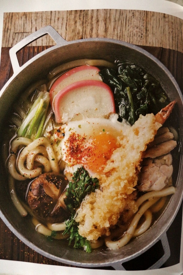 a bowl of udon noodle soup with egg and tempura fried shrimp