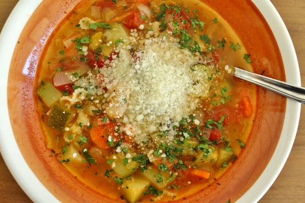 overhead view of a bowl of minestrone soup with Parmesan cheese