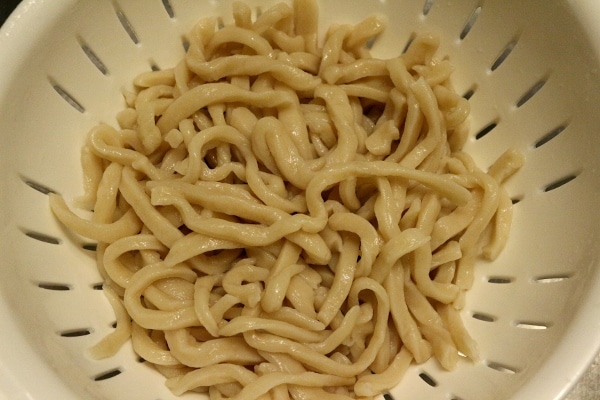 boiled udon noodles in a colander