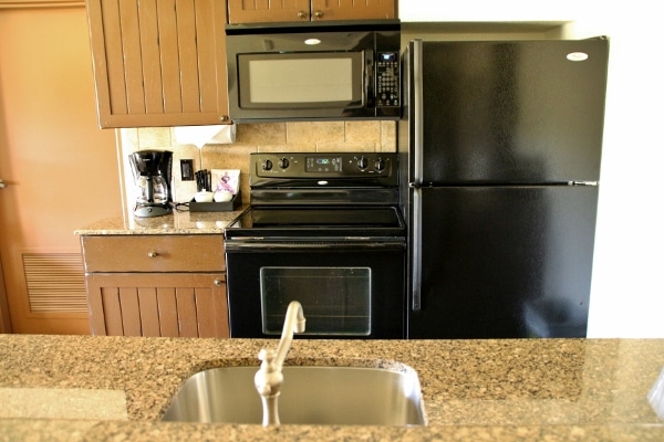 A kitchen with stove, microwave, refrigerator, sink, and granite counter tops