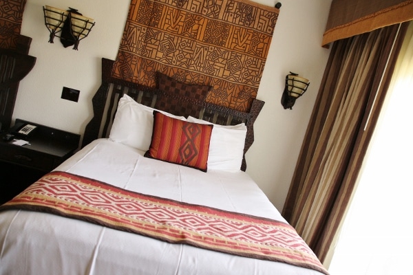 a queen size bed with an African tapestry hanging on the wall behind it