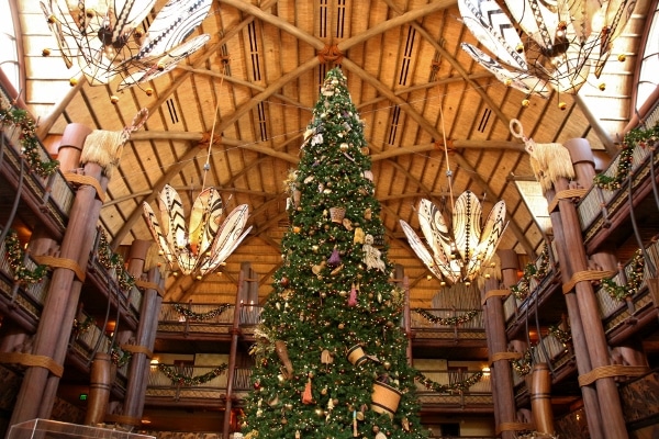 a large Christmas tree inside the lobby of Disney\'s Animal Kingdom Lodge - Jambo House