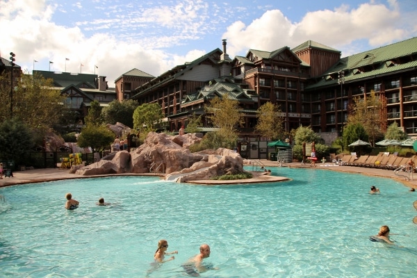 A group of people in a swimming pool with the Wilderness Lodge in the background