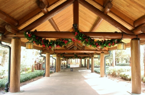 a covered walkway with Christmas garland hanging from a beam