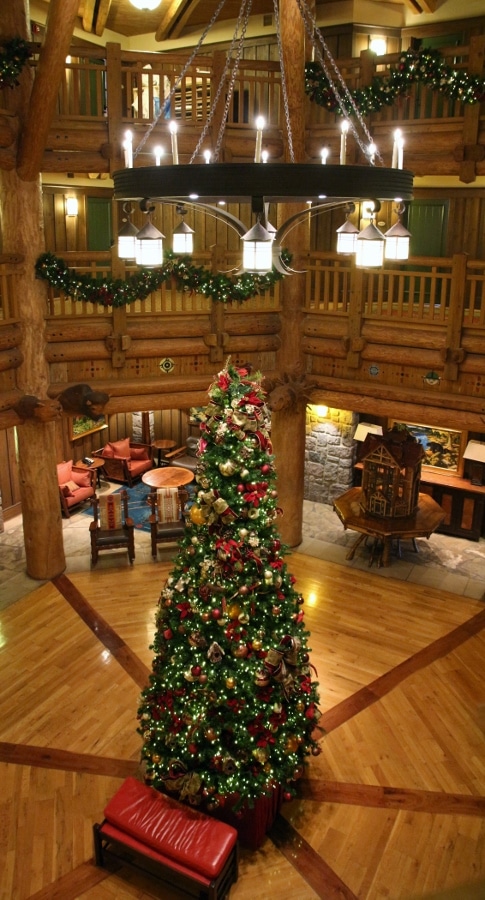 tall view of a Christmas tree in the center of a small wood-covered lobby