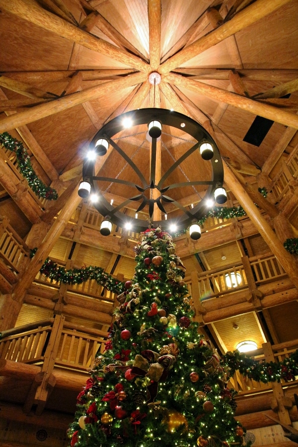view looking up at a Christmas tree beneath a circular light and wood beams