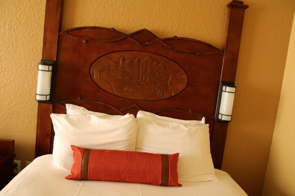 closeup of a bed in a hotel room with a carved wooden headboard