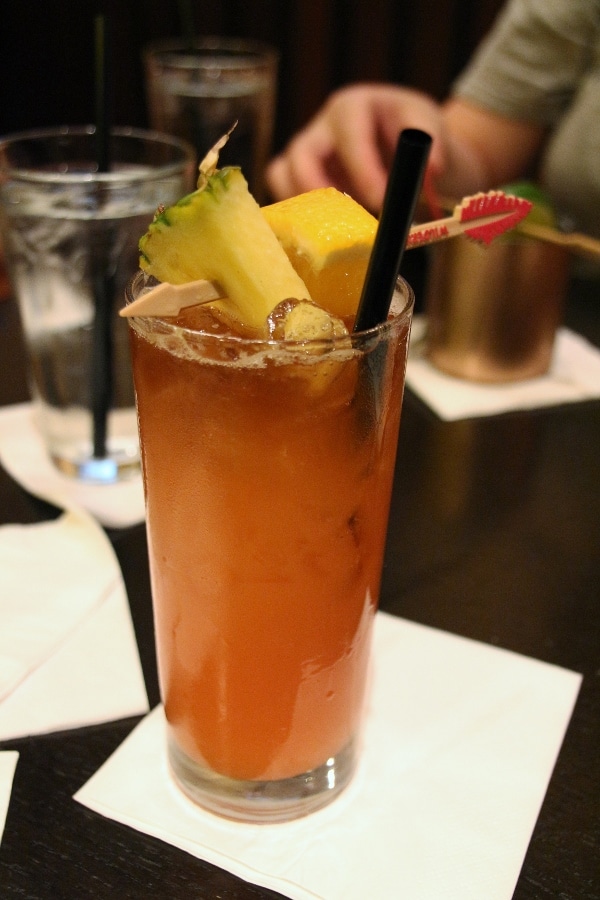 a tropical cocktail in a tall glass with a pineapple garnish