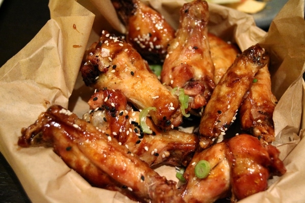 a basket of fried chicken wings with sesame seeds