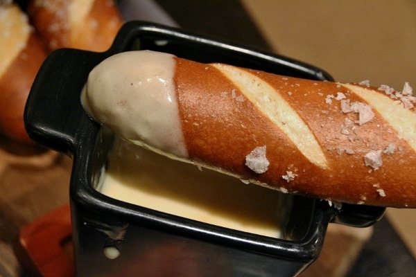 a closeup of a pretzel bread stick with cheese fondue on one end