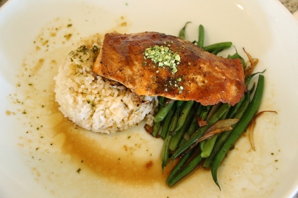 a salmon fillet served with rice and green beans on a white plate