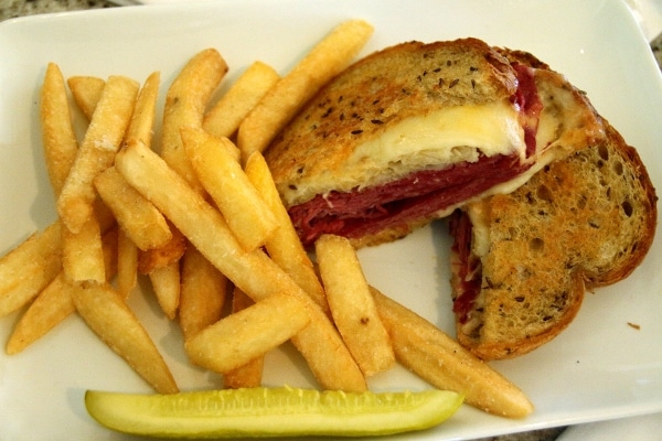 A sandwich cut in half, served with fries and a pickle spear