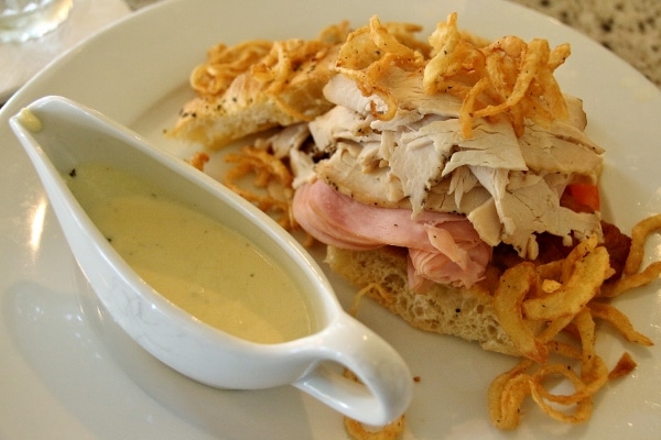 an open-faced sandwich with fried onions on top and sauce on the side