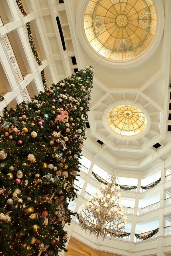 view looking up at a tall Christmas tree in a vast hotel lobby