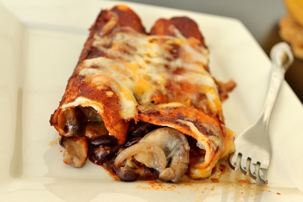 a closeup of enchiladas on a plate showing the mushroom and black bean filling