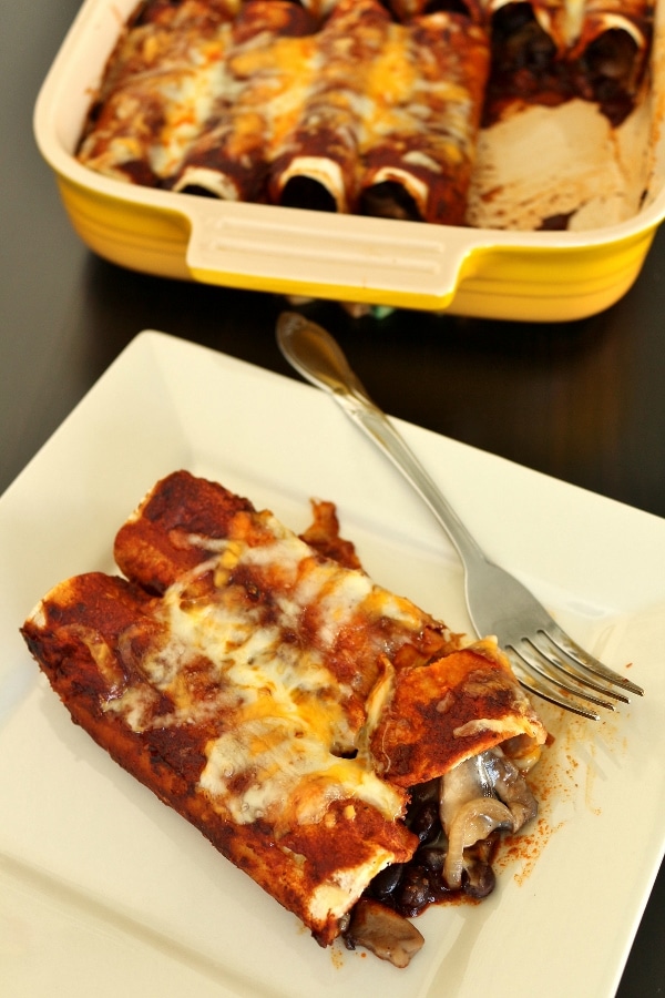 A plate of enchiladas with a casserole dish in the background