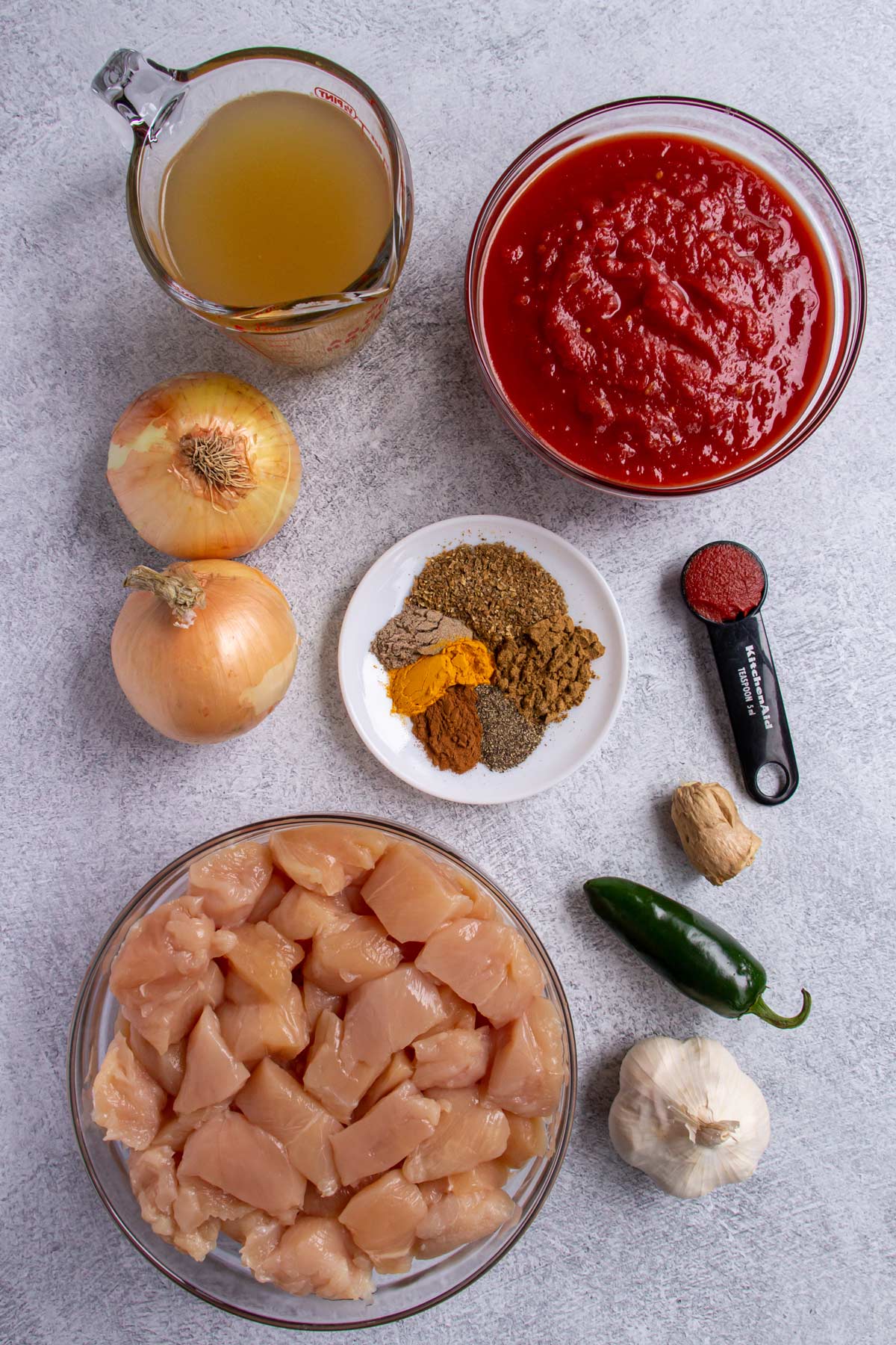 Ingredients for Cape Malay chicken curry on a grey background.