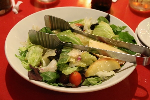 a bowl of salad with tongs