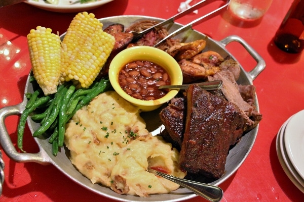 closeup of a large skillet with various BBQ meats, mashed potatoes, corn, and beans