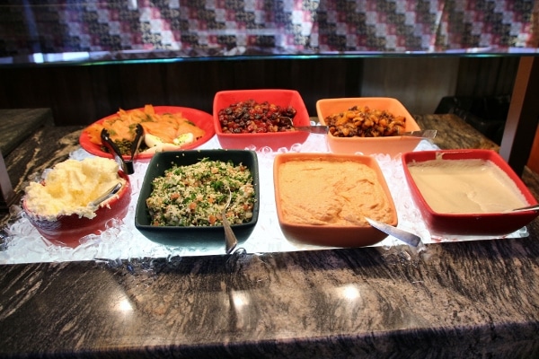 a variety of cold salads and hummus on a buffet line