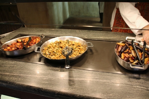 a variety of hot side dish options on a buffet line