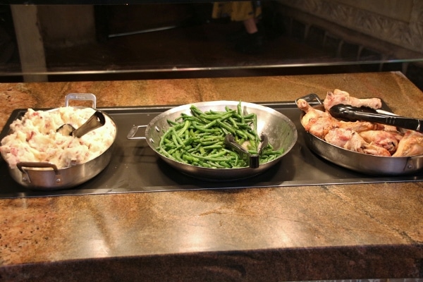 mashed potatoes, green beans, and chicken pieces on a buffet