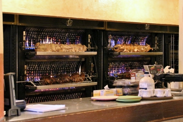 meats roasting on spits behind a counter