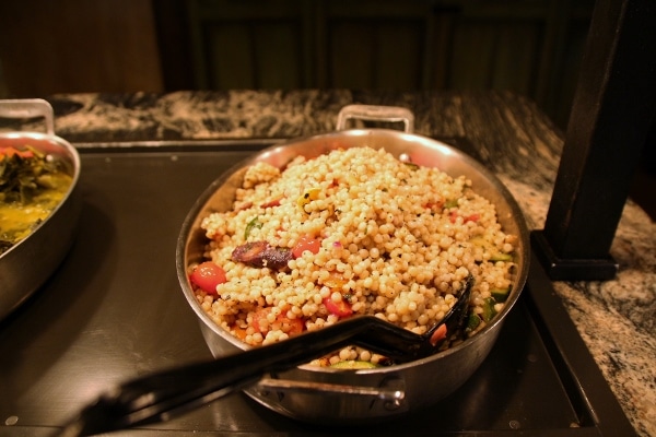 a pan of couscous with vegetables on a buffet line