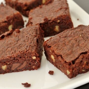 a closeup of brownies with walnuts and chocolate chips on a white plate