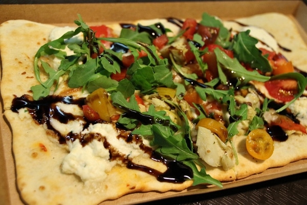 a flatbread pizza with tomatoes, arugula, and balsamic