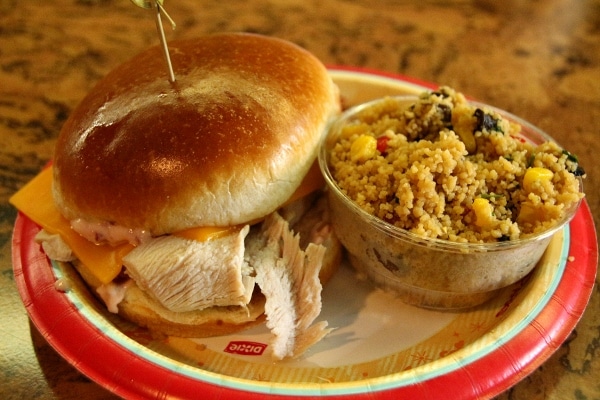 A sandwich sitting on a plate with a side of couscous salad