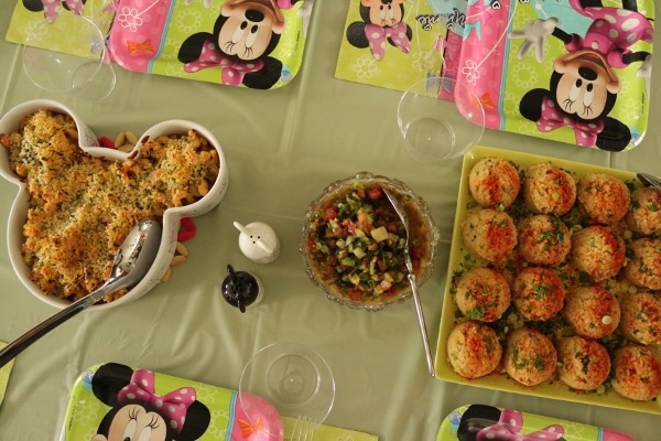 a table set for a child\'s birthday party with Minnie Mouse decorations and food